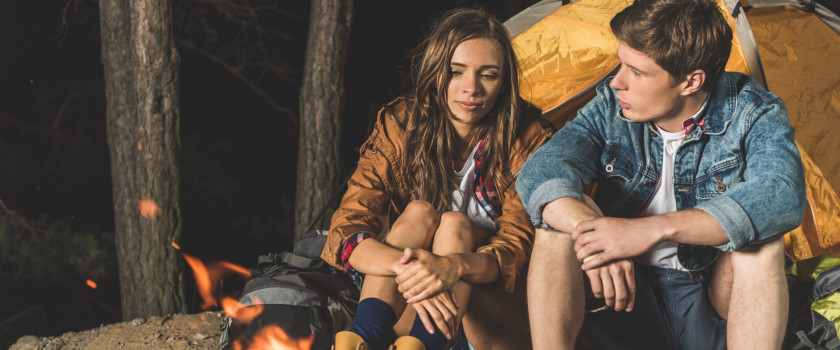 Happy hikers sitting next to a campfire.