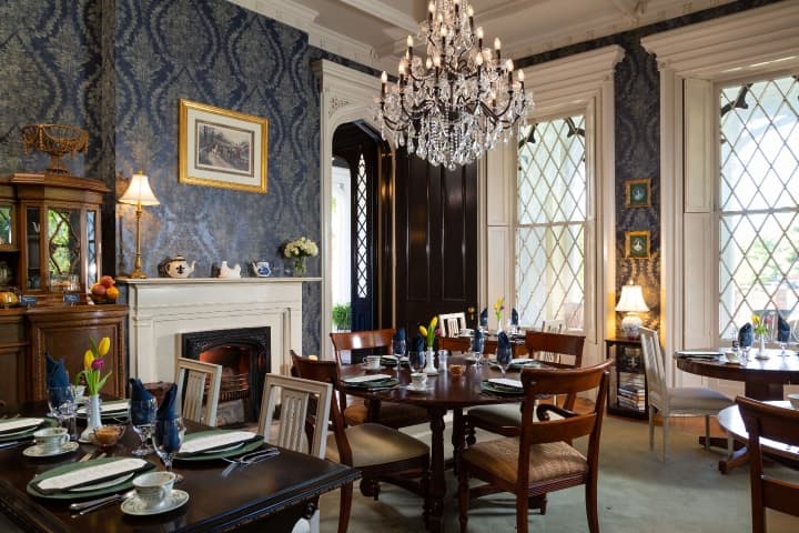 dining room with navy wallpaper, crystal chandelier and fireplace