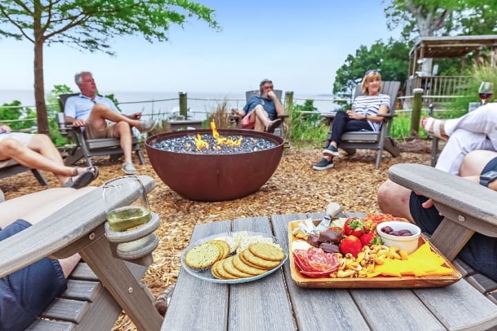 Guests enjoying charcuterie board around firepit at Jubilee Suites in Fairhope, AL