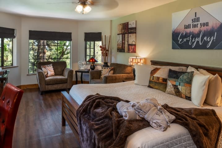 guest room with king bed in front of large windows with 2 oversized chairs in front of them