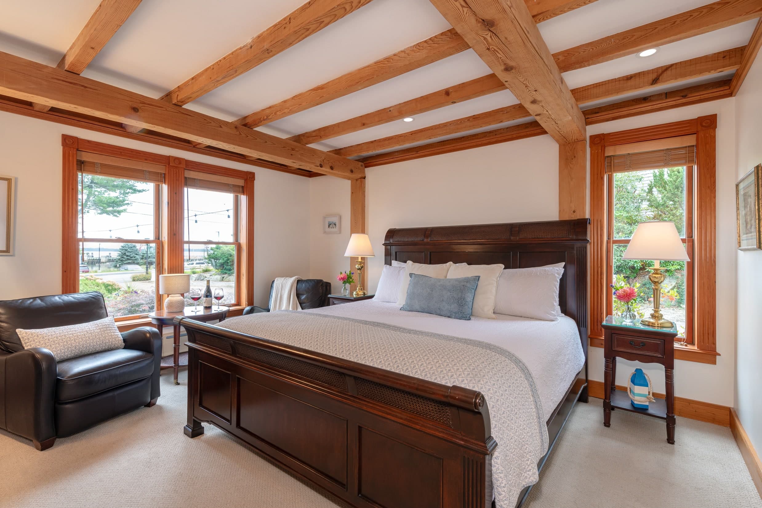 Photo of a room at the Spouter Inn Bed and Breakfast; beautifully exposed wooden beams frame the ceiling, while the the large king bed sits in a sleigh style frame.