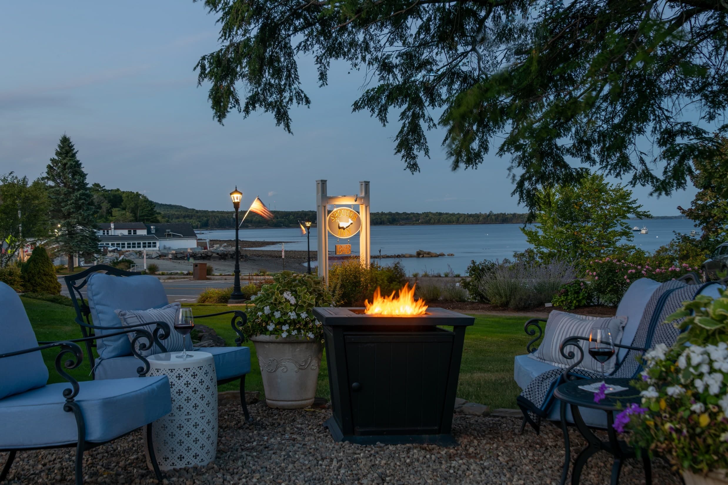 Waterside fire pit set on gravel against a backdrop of the bay at Spouter Inn Bed and Breakfast.
