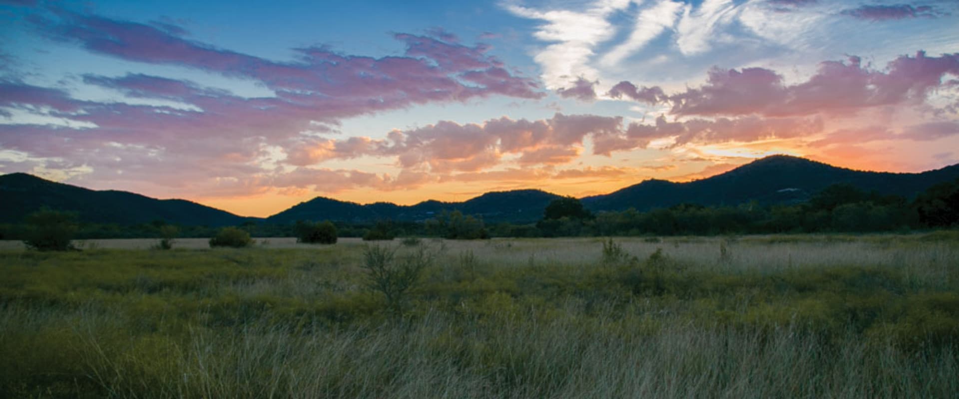The sun setting below mountains.
