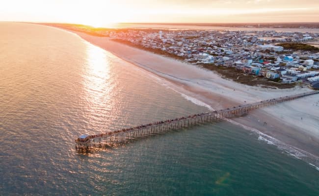 A long pier on the beach at sunset in North Carolina.
