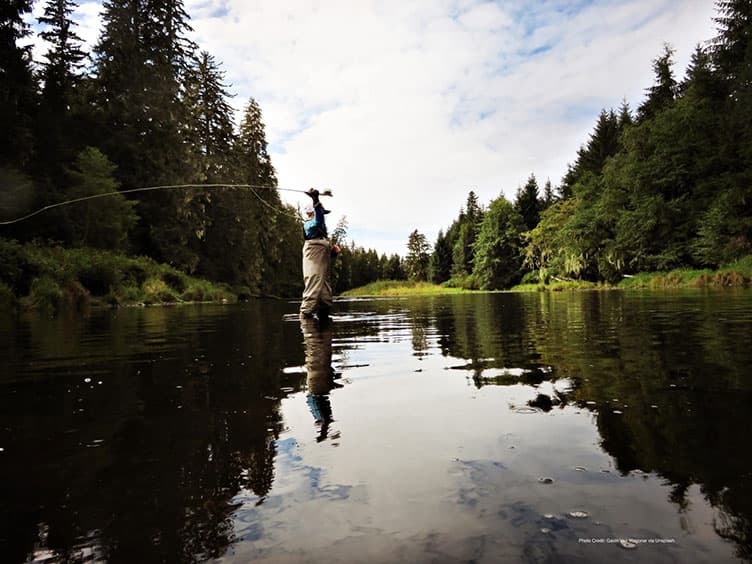 Man fly-fishing in a river in the middle of nature