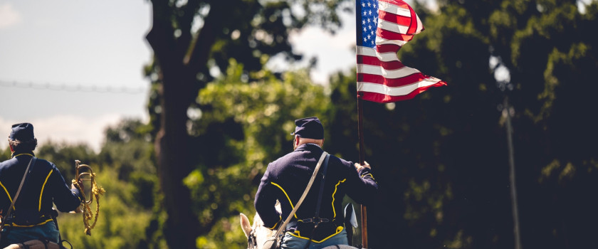 A confederate reenactor riding a horse with a flag