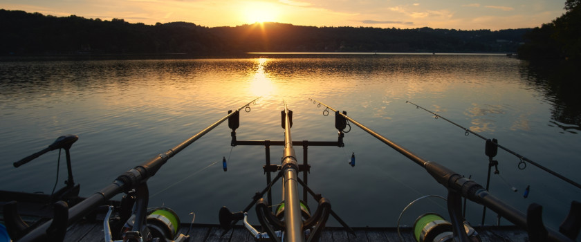 Two fishing rods on a lake at sunset