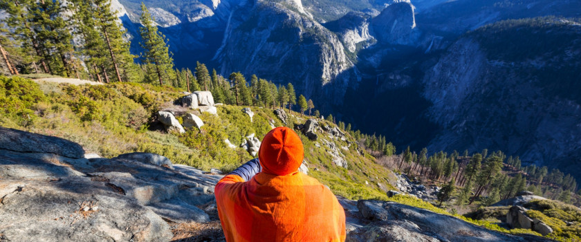 A person sitting on a rock wall overlooking Yosemite National Park