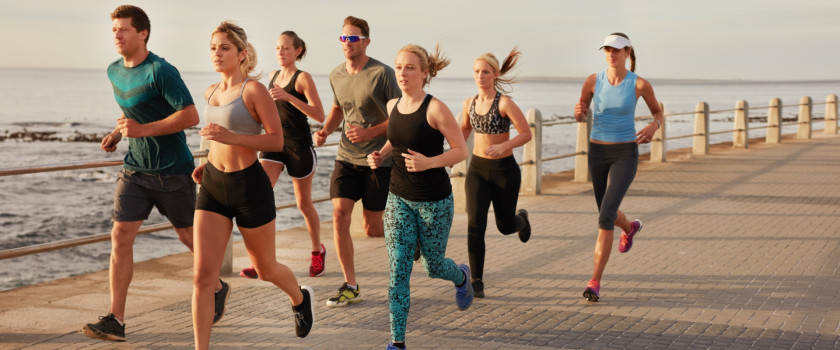 A group of people running along a beach boardwalk