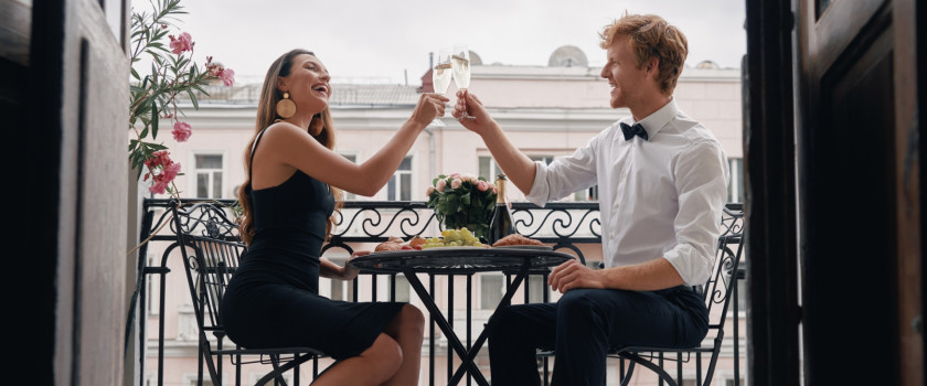 A smiling couple toasting with champagne on a terrace