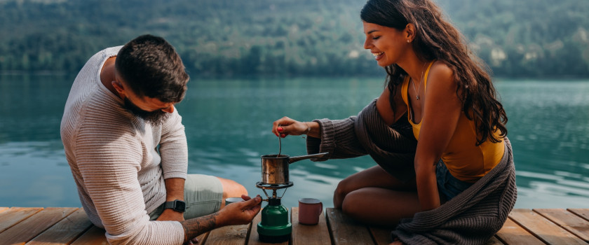 A romantic couple cooking on a camping burner on a dock.
