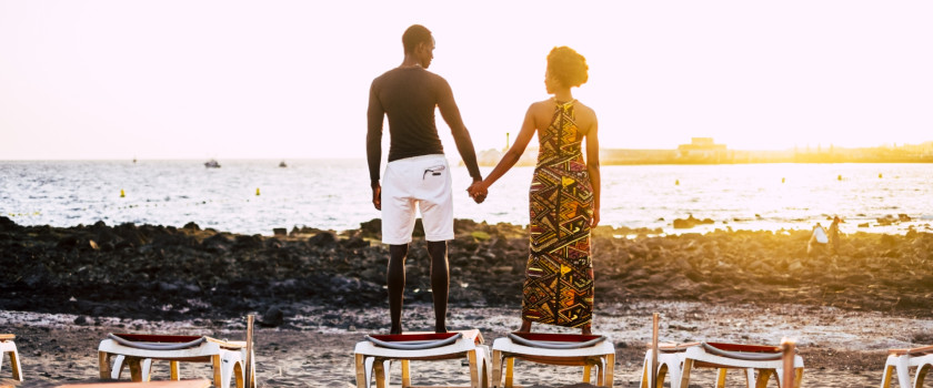 A romantic couple overlooks the water at sunset.