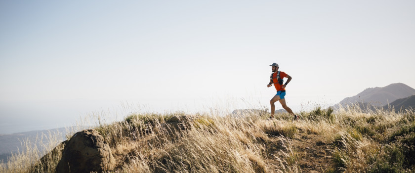 Person running outdoors in rural, hilly setting.