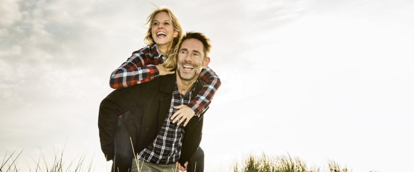 Happy couple playing on beach dunes.