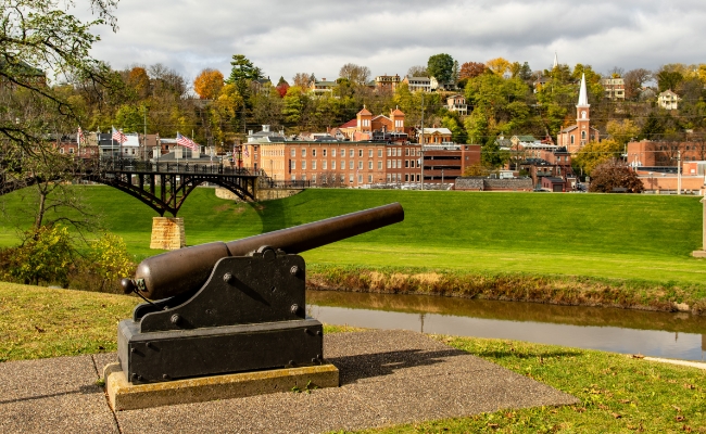 antique war cannon looking over green hills