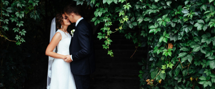 Bride and groom kissing beneath a tree