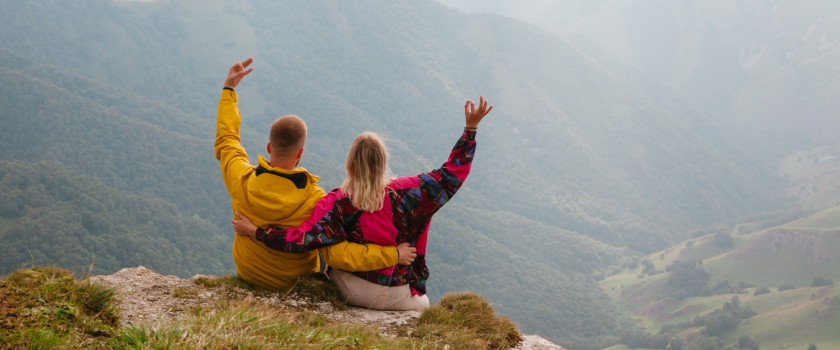 Couple sitting atop a rock edge overlooking a valley