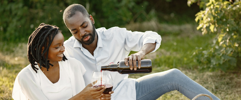 A couple pouring wine at a summer picnic