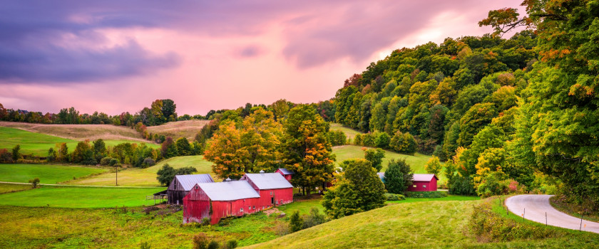 Farmland with red barns in Vermont at sunset.