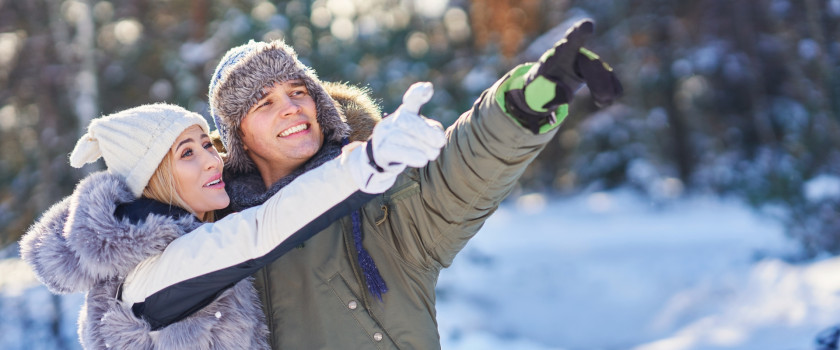 Couple in snow clothes pointing in a winter scenery