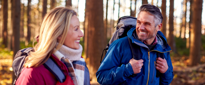 Side view of a couple hiking in fall with backpacks