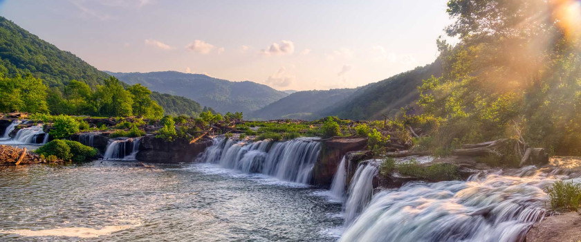 Sandstone Falls at New River Gorge National Park in West Virginia with green mountains and cascading waterfalls