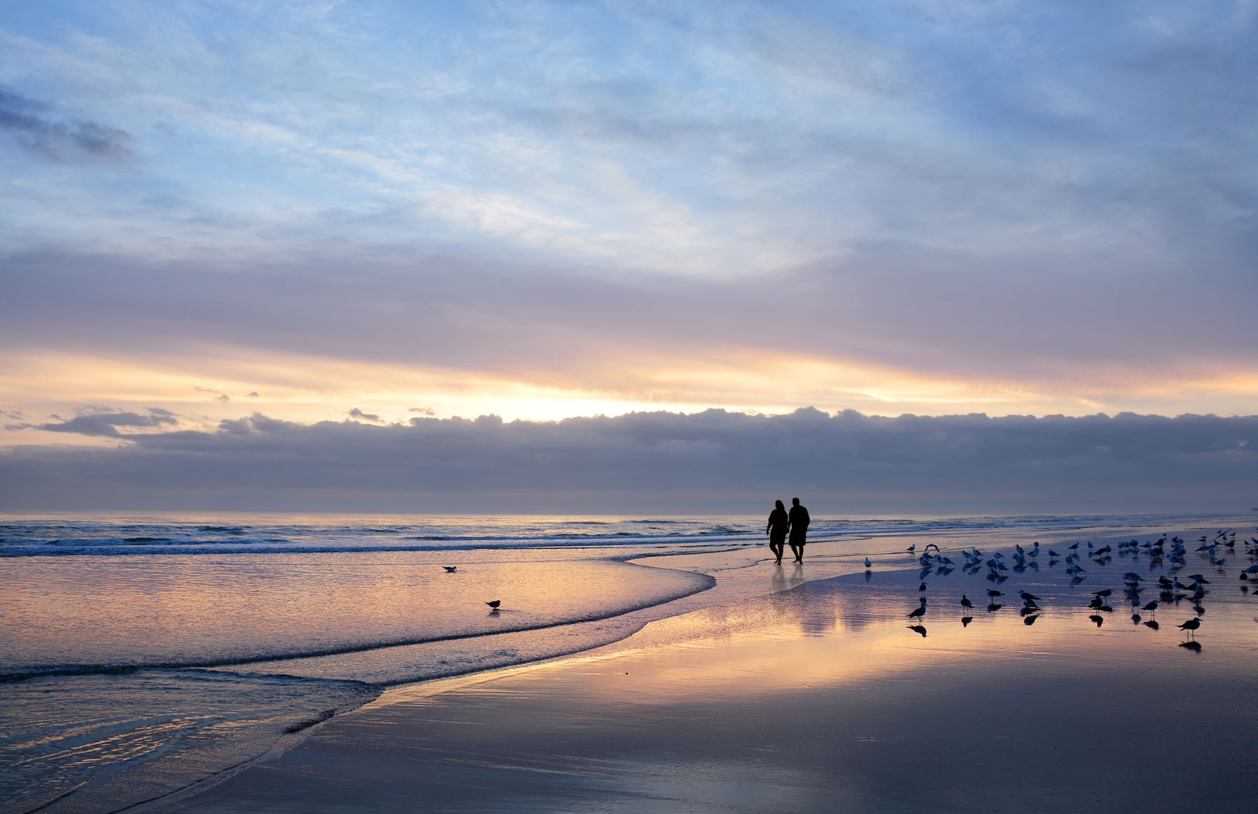 A couple walking on a Florida beach at sunrise: romantic getaways on the East Coast.