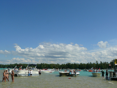people hanging out in the water at torch lake with their boats