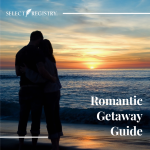 Access Our Romantic Getaway Guide! Couple standing on the beach looking out over the sunset.