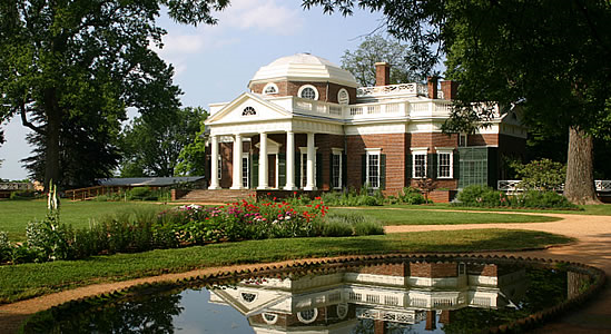 view of Monticello, brick mansion with white columns, green lawn and pond