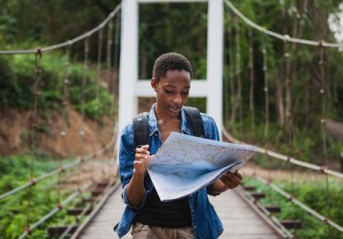 woman looking over a map on a bridge while exploring nature at a top travel destination