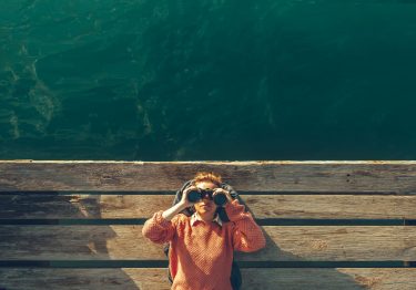 Girl with Binoculars on pier by the sea