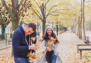 Couple in the Fall throwing leaves having fun