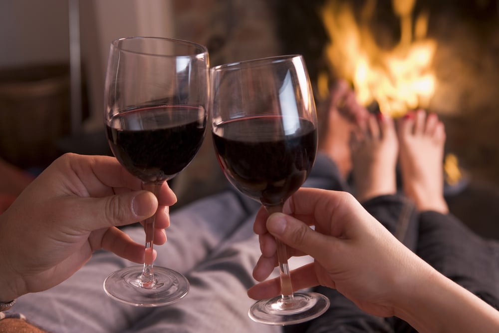 A couple drinking wine by the fire during their romantic getaways in Pennsylvania
